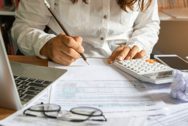 woman working at her desk, writing down notes and using a calculator