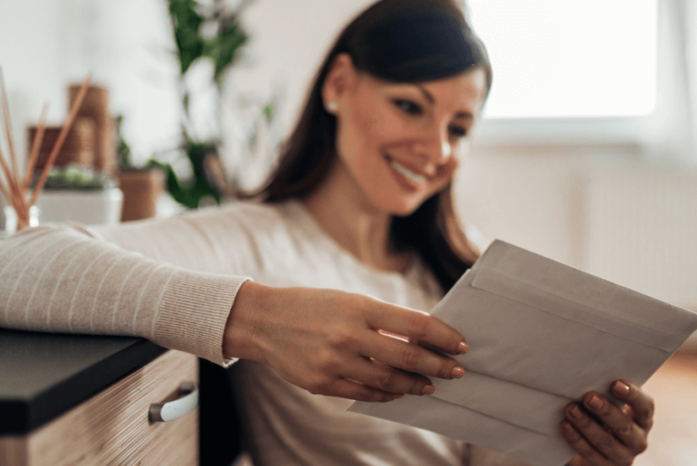 Cheerful woman checking received mail at home, focus on a mail